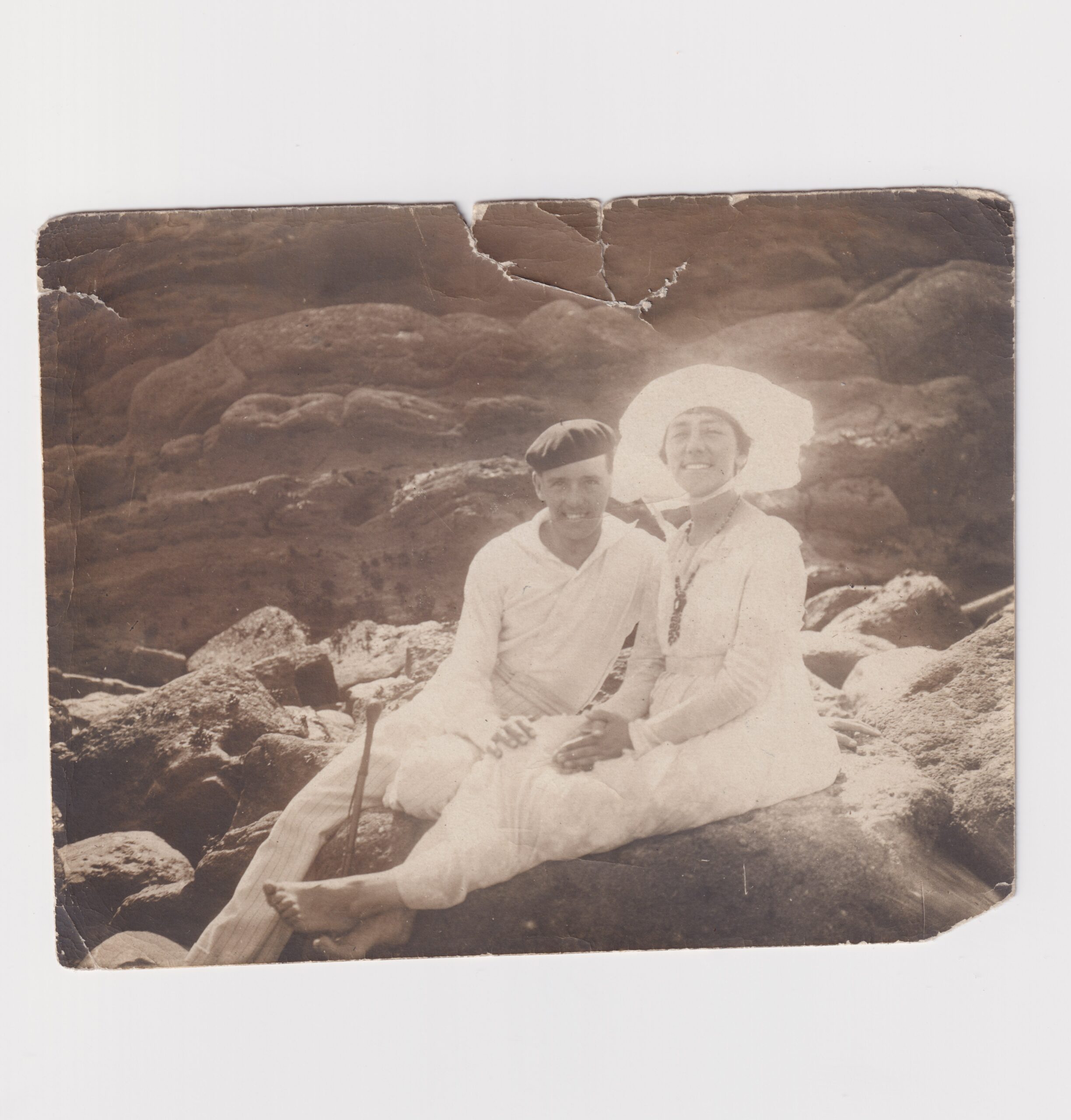 Hombre y mujer sentados en una roca con traje de baño.