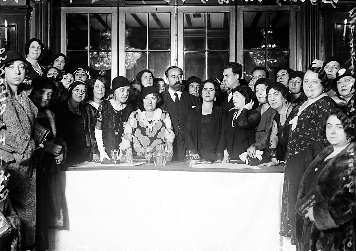 Varias personas alrededor de una mesa, mirando a cámara.