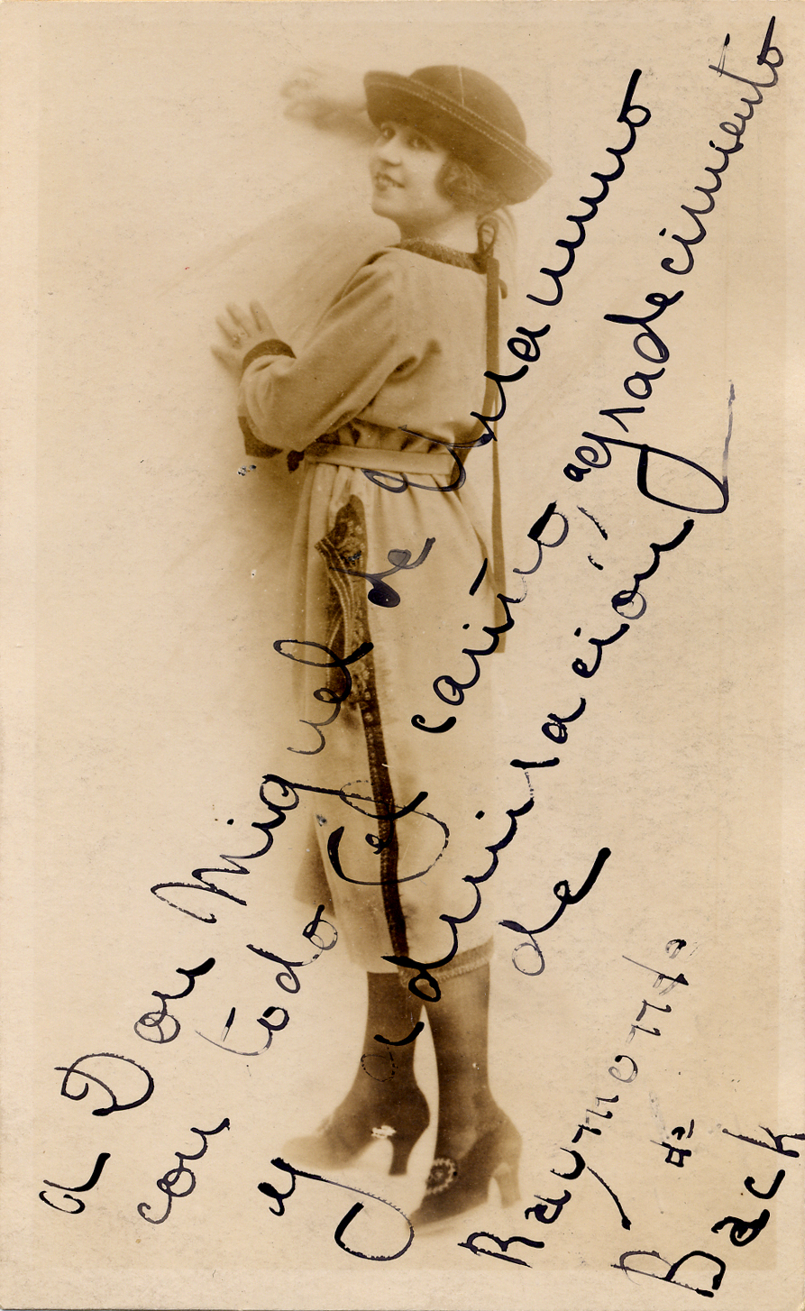 Mujer con sombrero, de pie apoyada en una pared, mirando hacia arriba