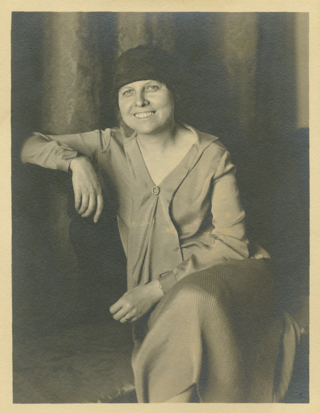 Mujer sentada con el brazo apoyado en alto.