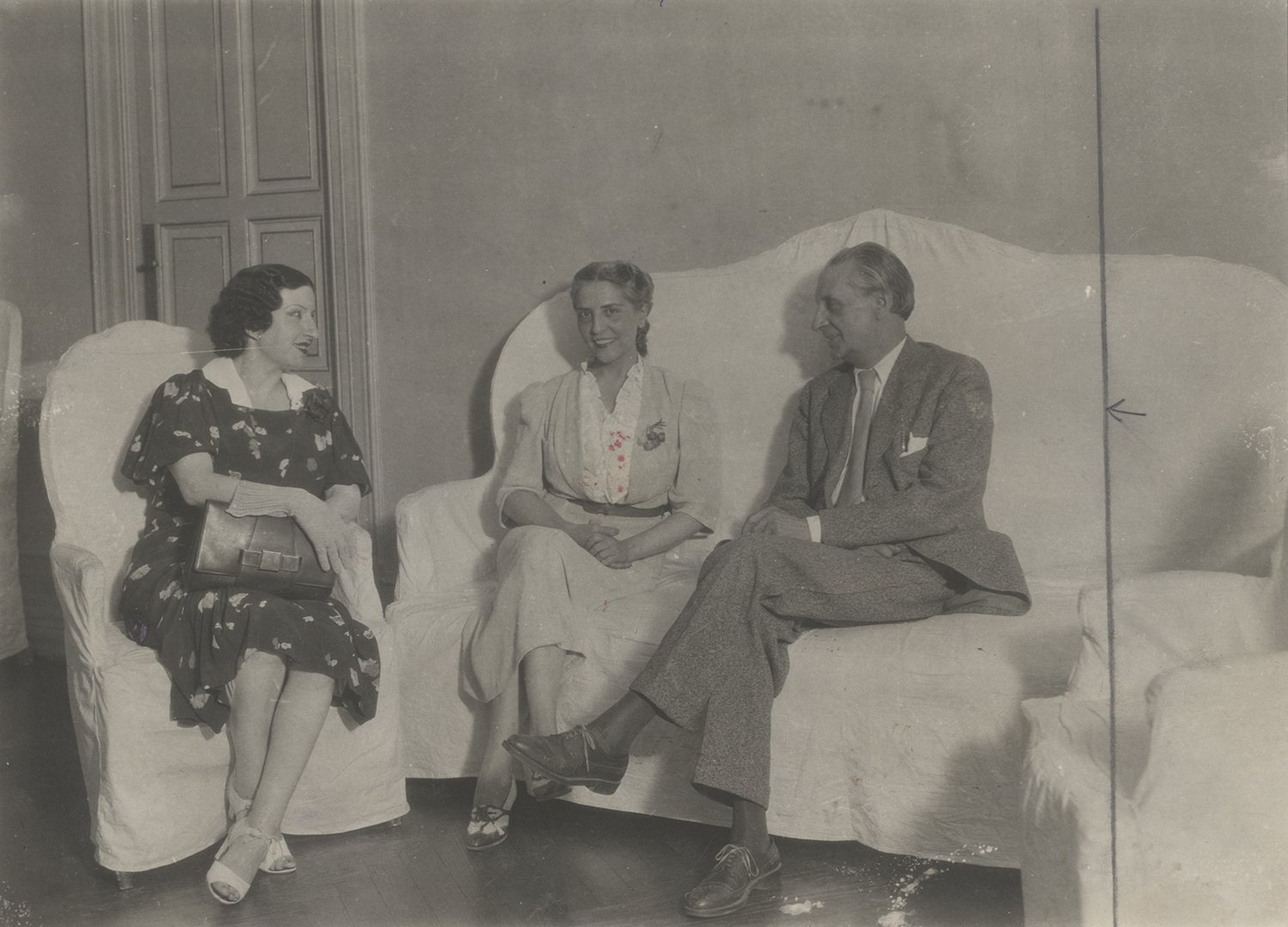 Dos mujeres y un hombre conversando en unos sillones.