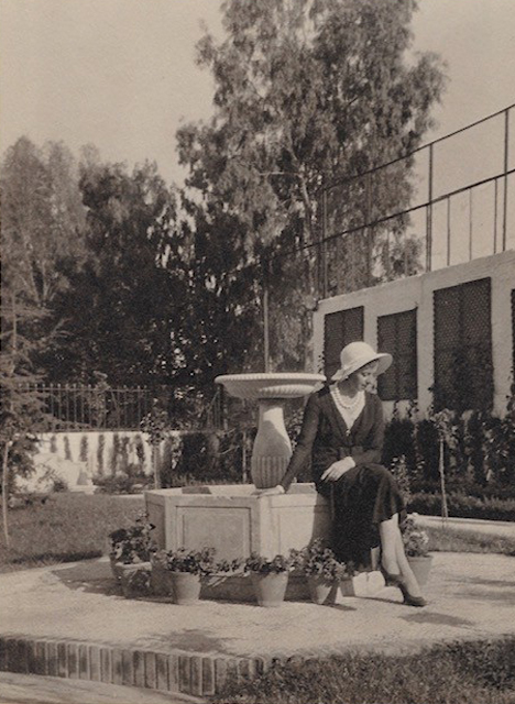 Mujer sentada en la fuente de un jardín.