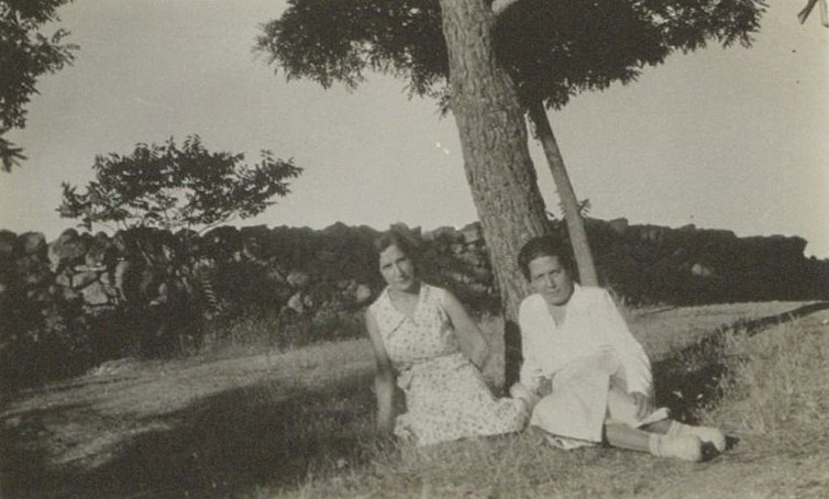 Dos mujeres sentadas bajo un árbol.