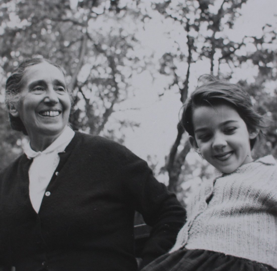 Mujer y niña riendo, con árboles de fondo.