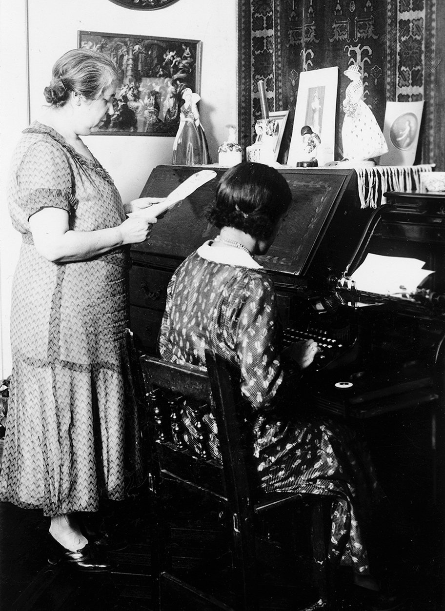 Una mujer dictando a otra, que está escribiendo a máquina.