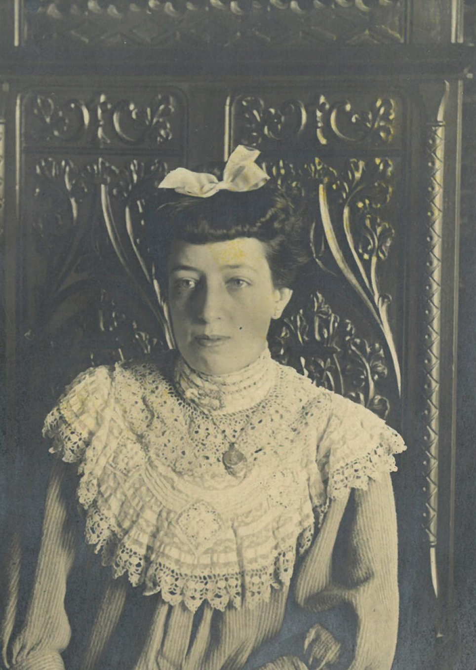 Retrato de mujer con vestido y lazo delante de un armario.