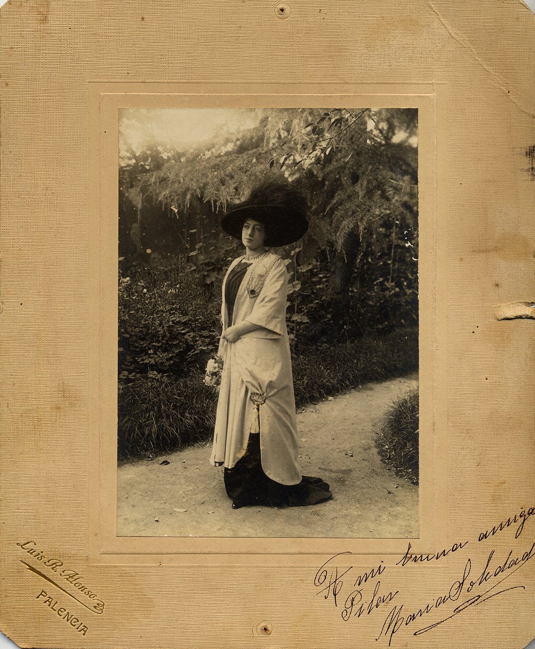 Mujer en jardín con sombrero grande.