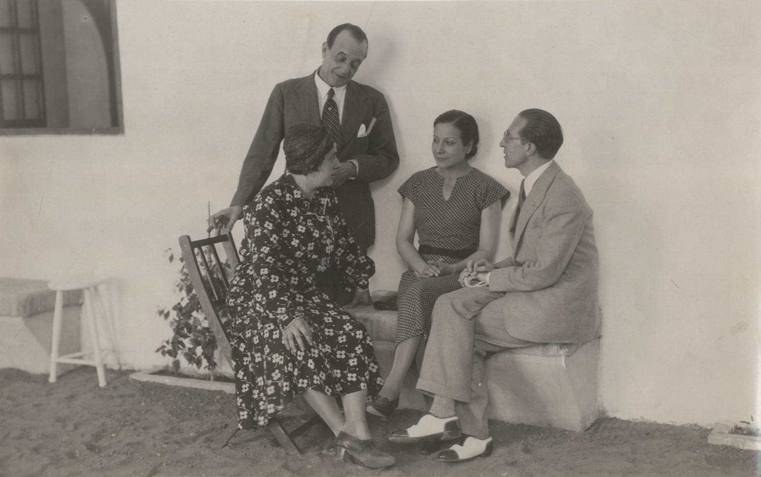 Dos hombres y dos mujeres sentados en un patio hablando.