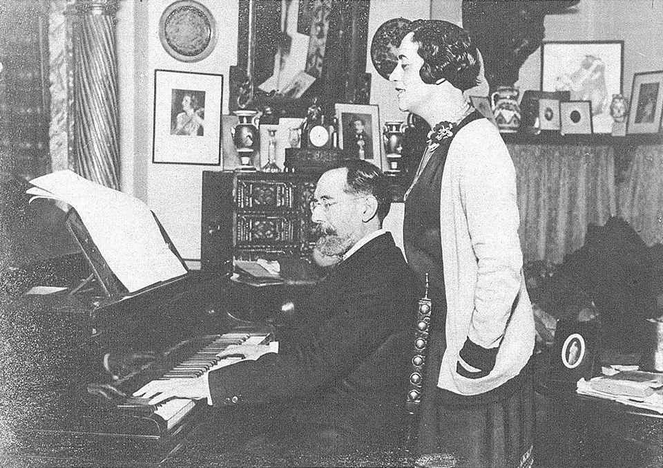 Fotografía de una pareja en su casa, con el hombre tocando el piano.