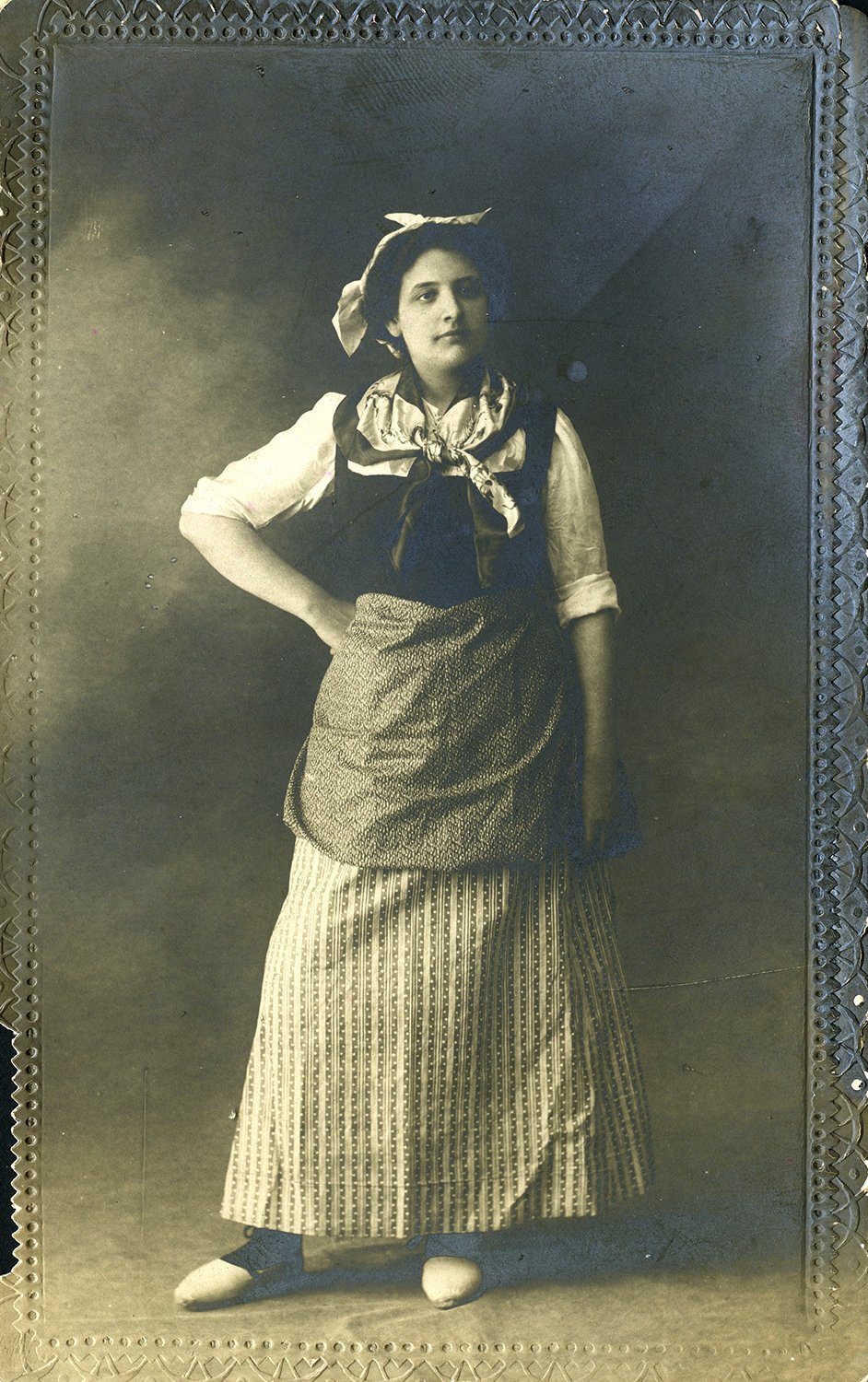Mujer de pie con traje tradicional.