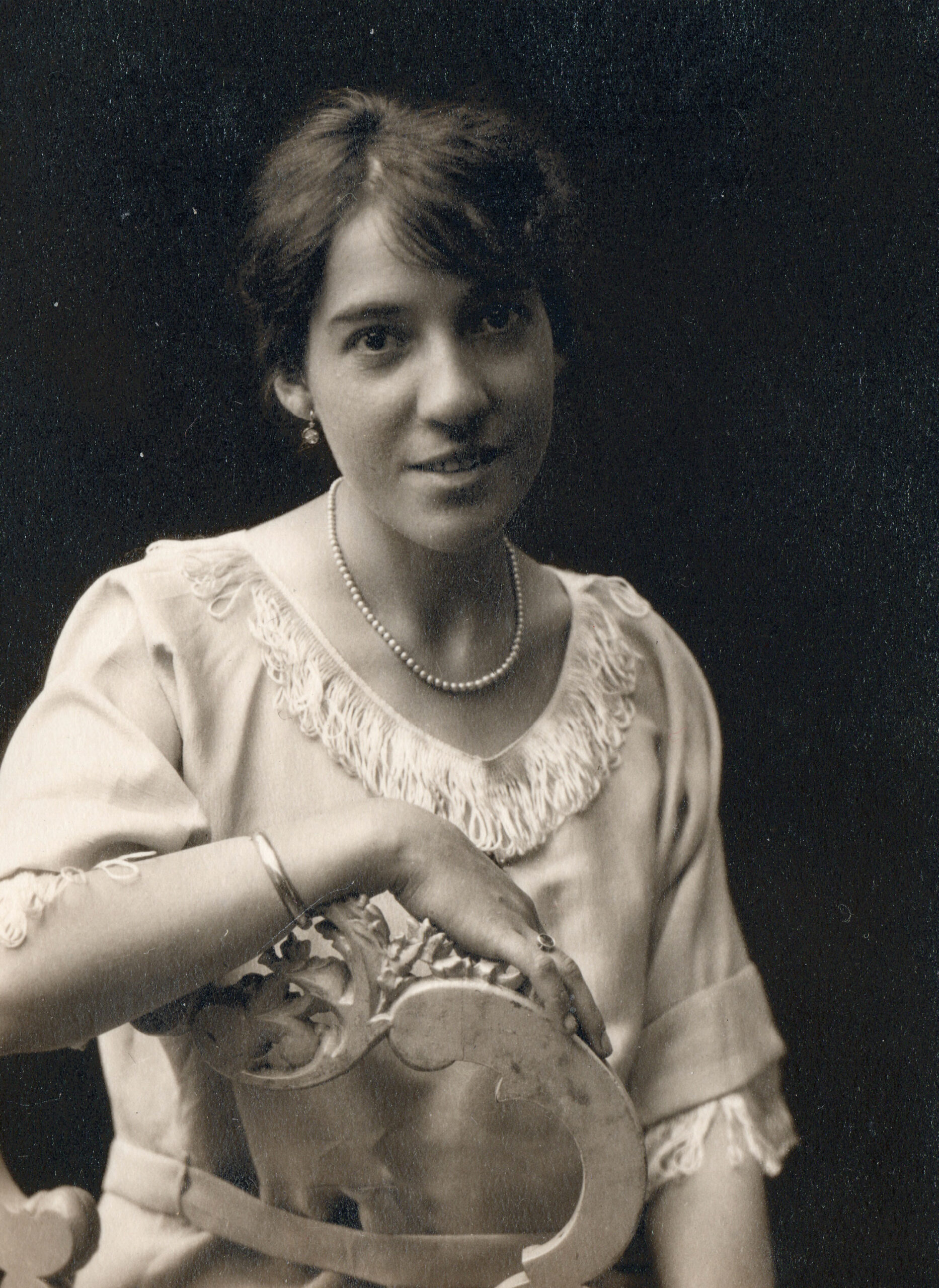 Retrato de mujer apoyada en una silla.