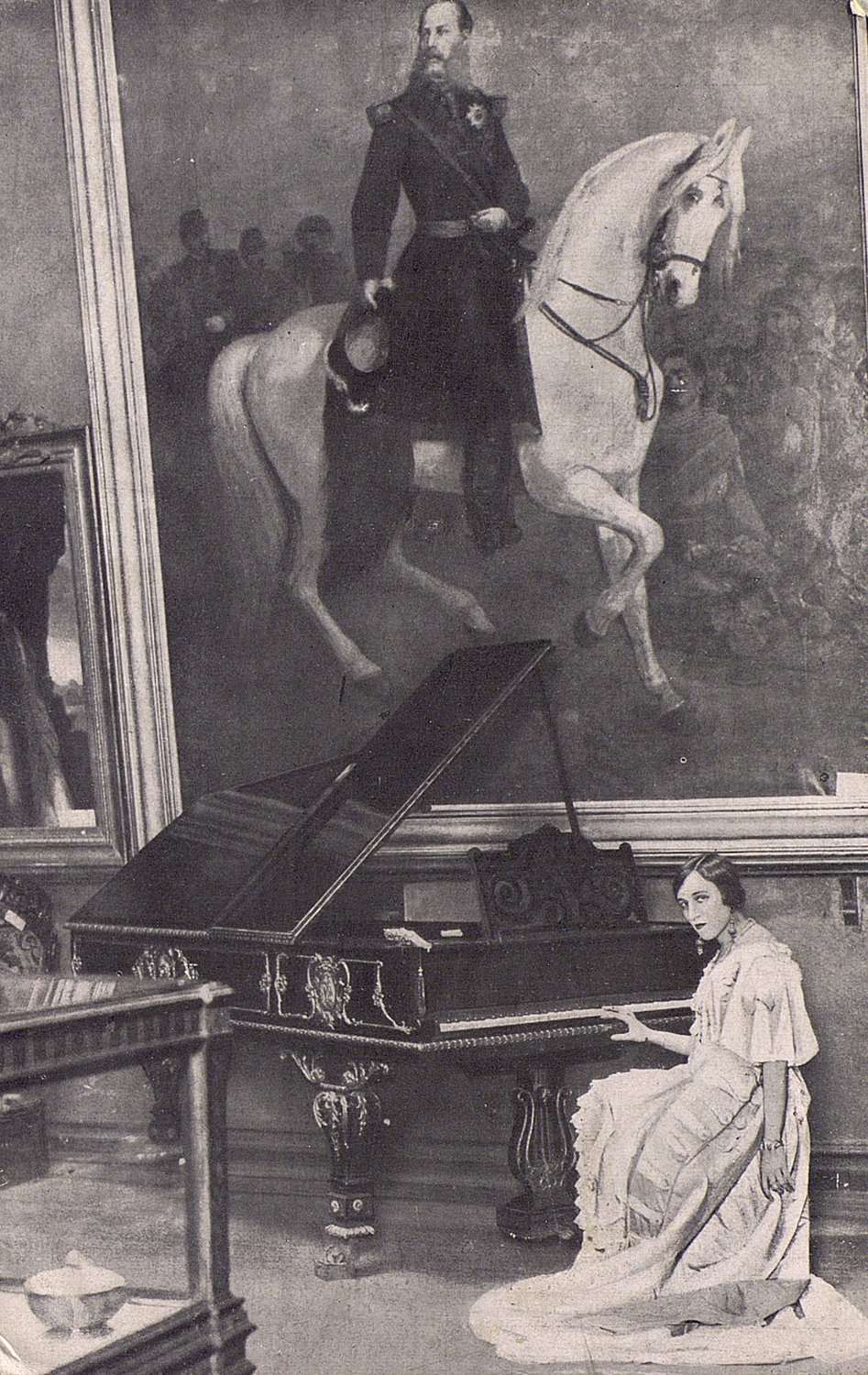 Mujer sentada delante de un piano, con un cuadro de un hombre a caballo ocupando toda la pared.
