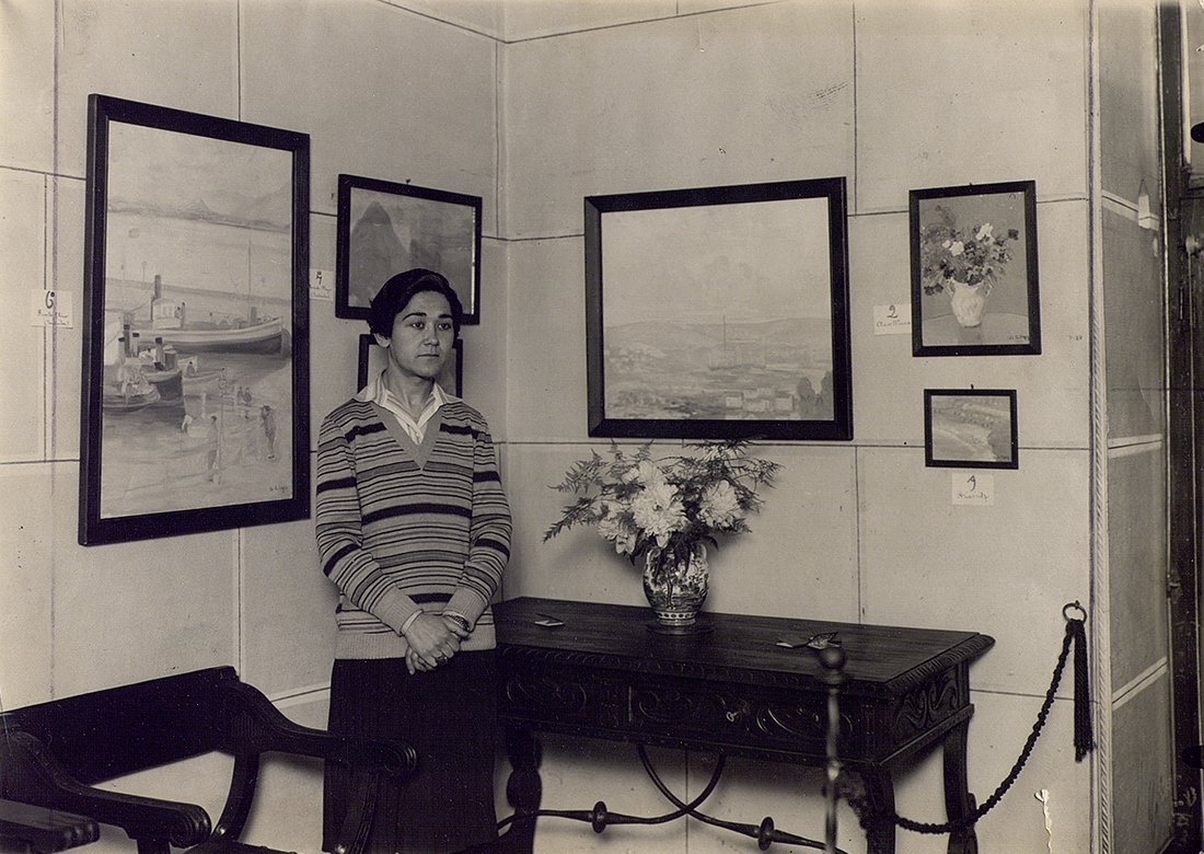 Mujer en una habitación, con cuadros en la pared.